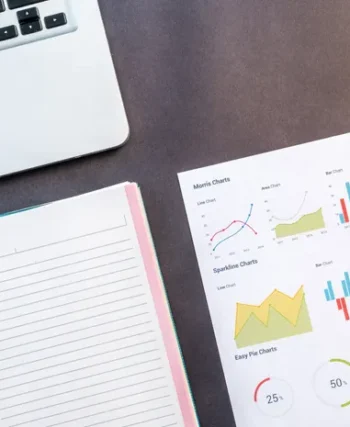 Laptop and data charts on a desk representing competitor research analysis