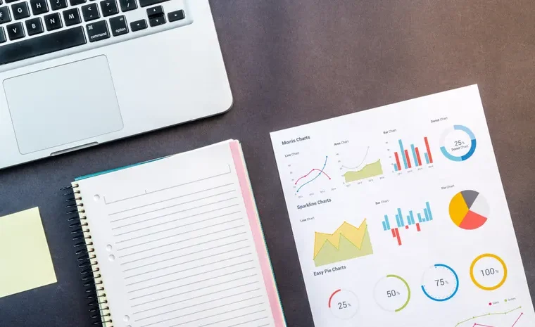Laptop and data charts on a desk representing competitor research analysis