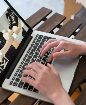 Person creating a fashion product collection on a laptop for an online store