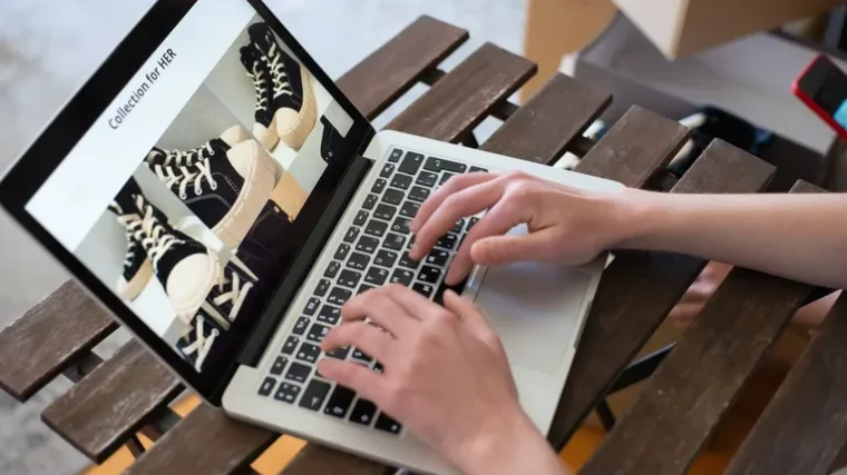 Person creating a fashion product collection on a laptop for an online store