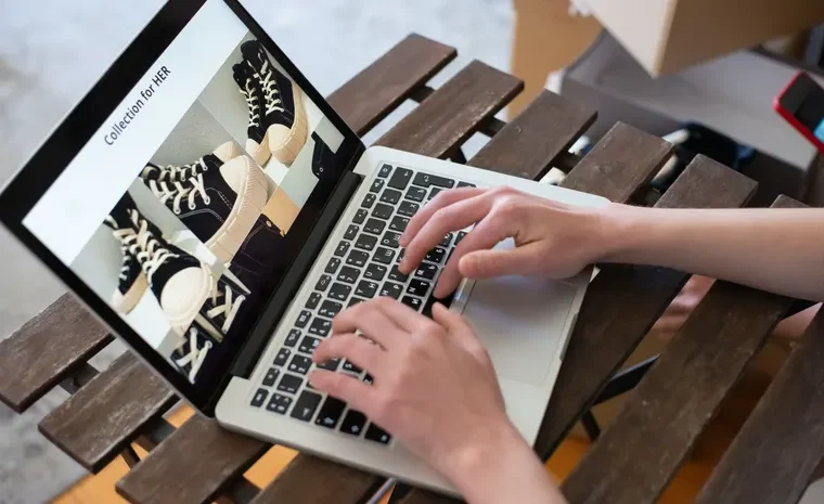 Person creating a fashion product collection on a laptop for an online store