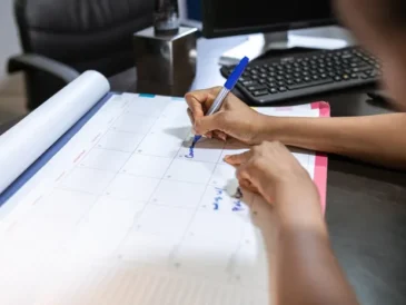 Person planning their schedule on a desk calendar using AI tools