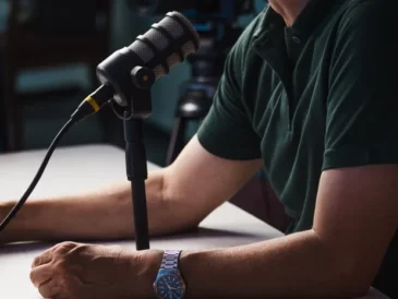 Person recording a podcast with a professional microphone in a studio