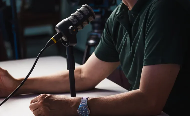 Person recording a podcast with a professional microphone in a studio