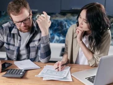 Person reviewing bills and subscription statements on a laptop