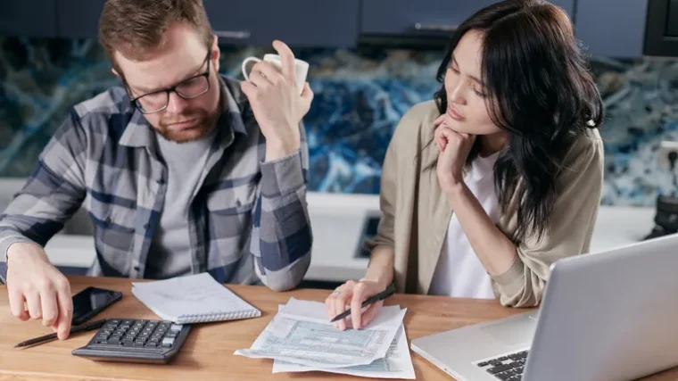 Person reviewing bills and subscription statements on a laptop