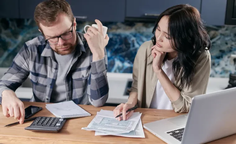 Person reviewing bills and subscription statements on a laptop