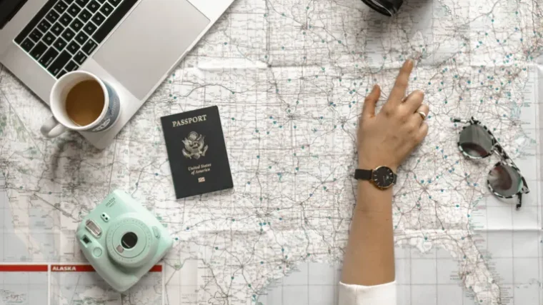 Hand pointing at a map with laptop and passport, planning a trip with AI